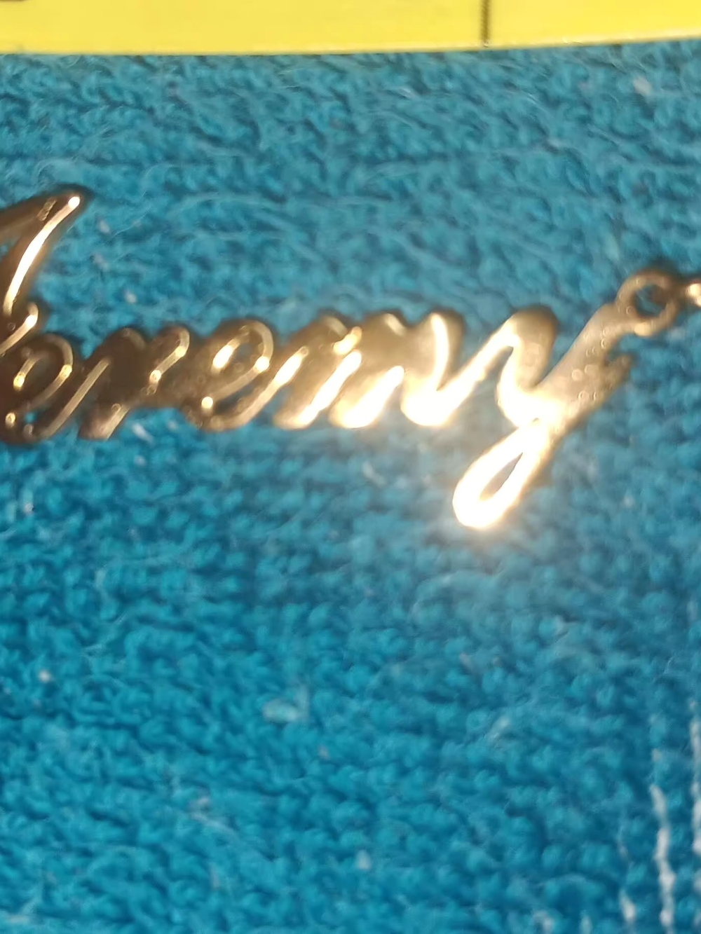 Gold Script Nameplate Necklace on Teal Fabric